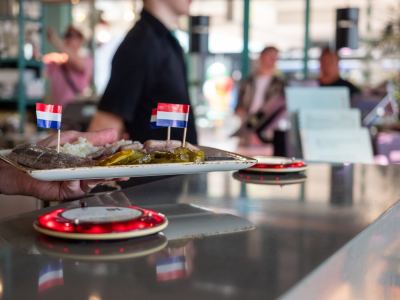 Bordje haring met uitjes en augurk, met Hollandse vlaggetjes erin