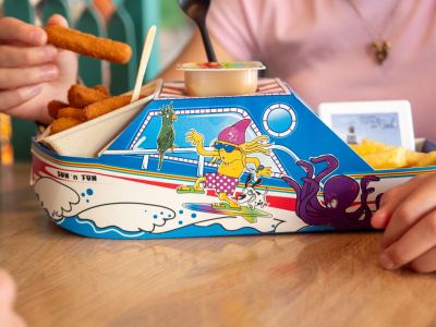 Kind eet vissticks en friet uit een kartonnen bootje