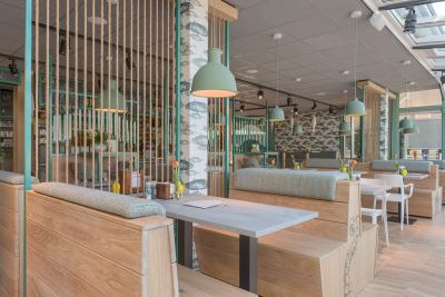 De eetzaal met houten tafels en zeegroene wanden