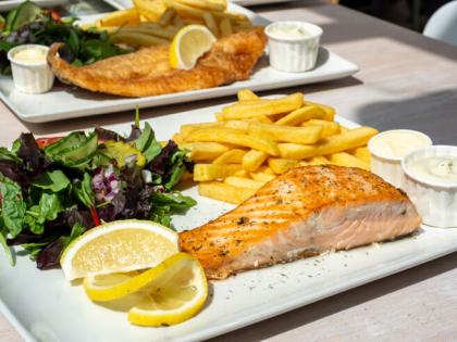 Bord met gebakken zalmfilet, friet, salade en citroen