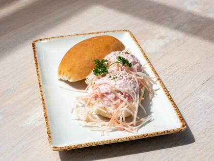 Broodje met romige krabsalade en peterselie op een wit bord